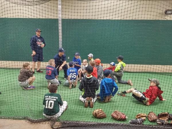 Cam Booser and Trey Vavra talking baseball with campers in the indoor batting cage